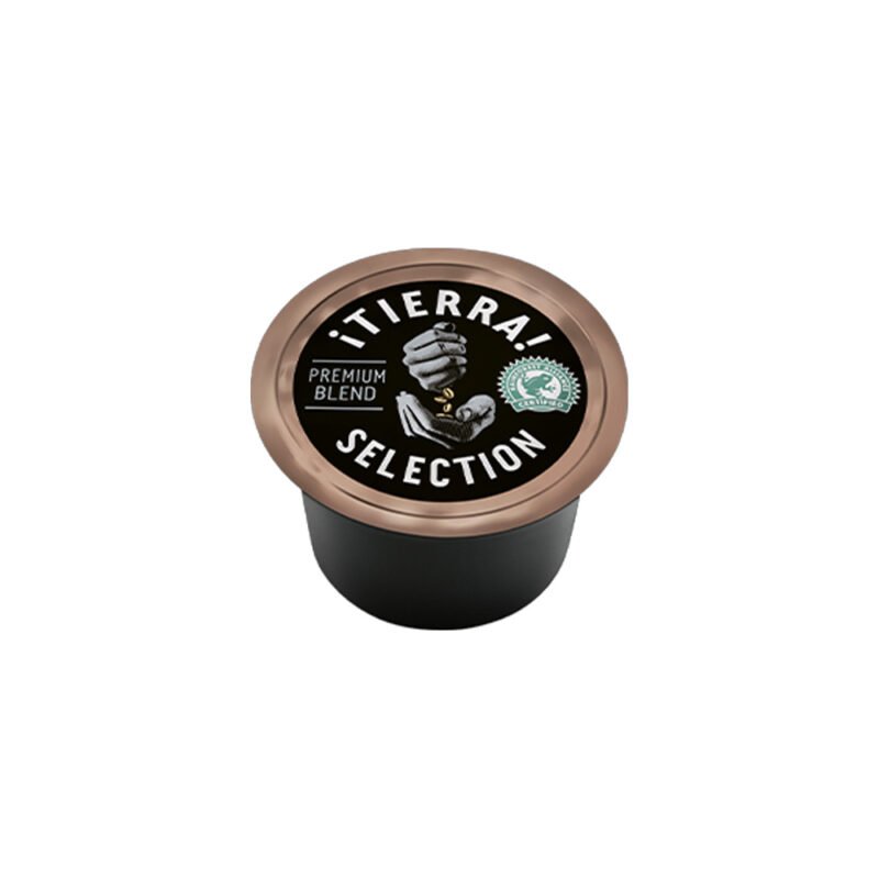 A coffee pod labeled "Tierra Selection" with "Premium Blend" written on it, reminiscent of a barista's craft. The lid features a graphic of an arm holding coffee plants, evoking the essence of a cozy café. The pod is set against a plain white background.