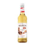 A bottle of Monin Honeycomb Syrup, perfect for any café or barista. The white and red label features honeycomb images, highlighting its natural flavor. The clear bottle showcases the syrup's golden color, ideal for crafting exquisite coffee creations.