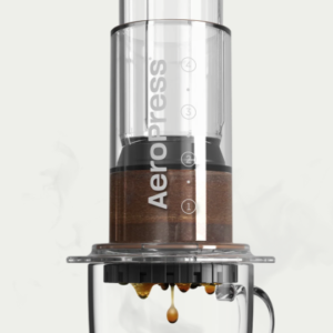 Aeropress portable coffee maker on top of a glass mug producing coffee