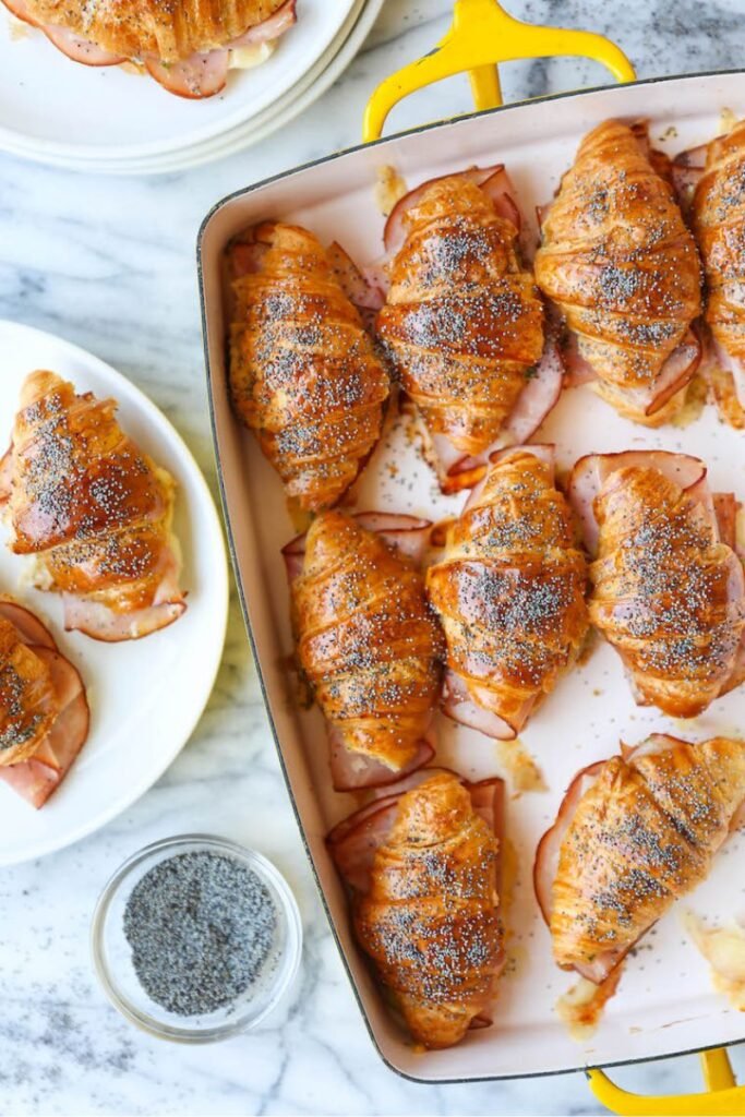 An enamel baking traywith a selection of freshly baked croissants with cheese and ham sprinkled with poppy seeds